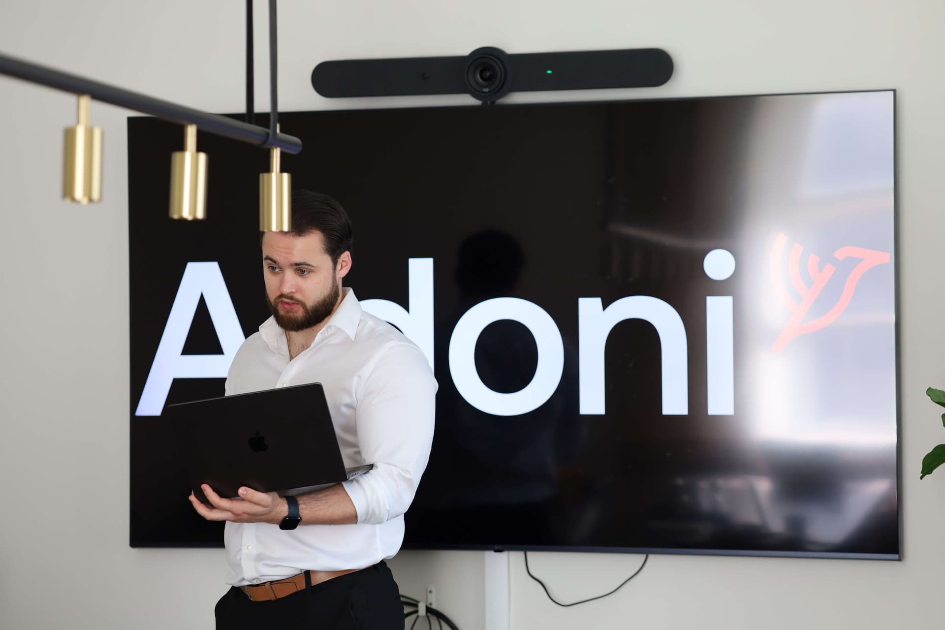 En Aidoni-konsult med laptop framför en skärm med Aidonis logotyp